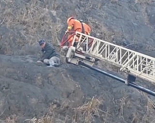 【新闻直播间】男子捡野菜被困峭壁 消防云梯助营救